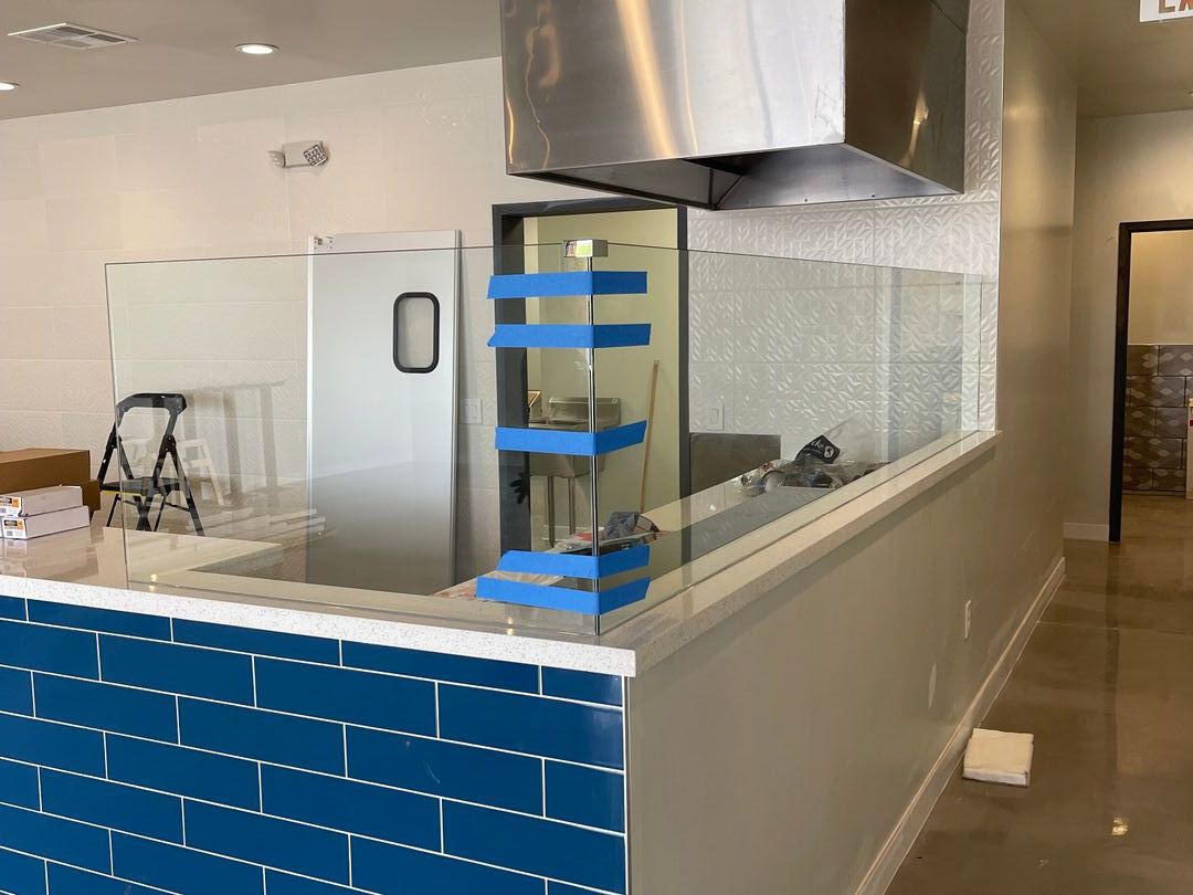 Glass partition wall above a blue tiled counter in a commercial kitchen