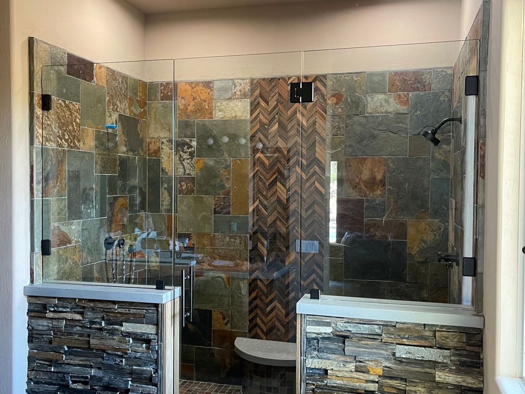Frameless glass shower enclosure with multicolor slate tile and a herringbone accent wall
