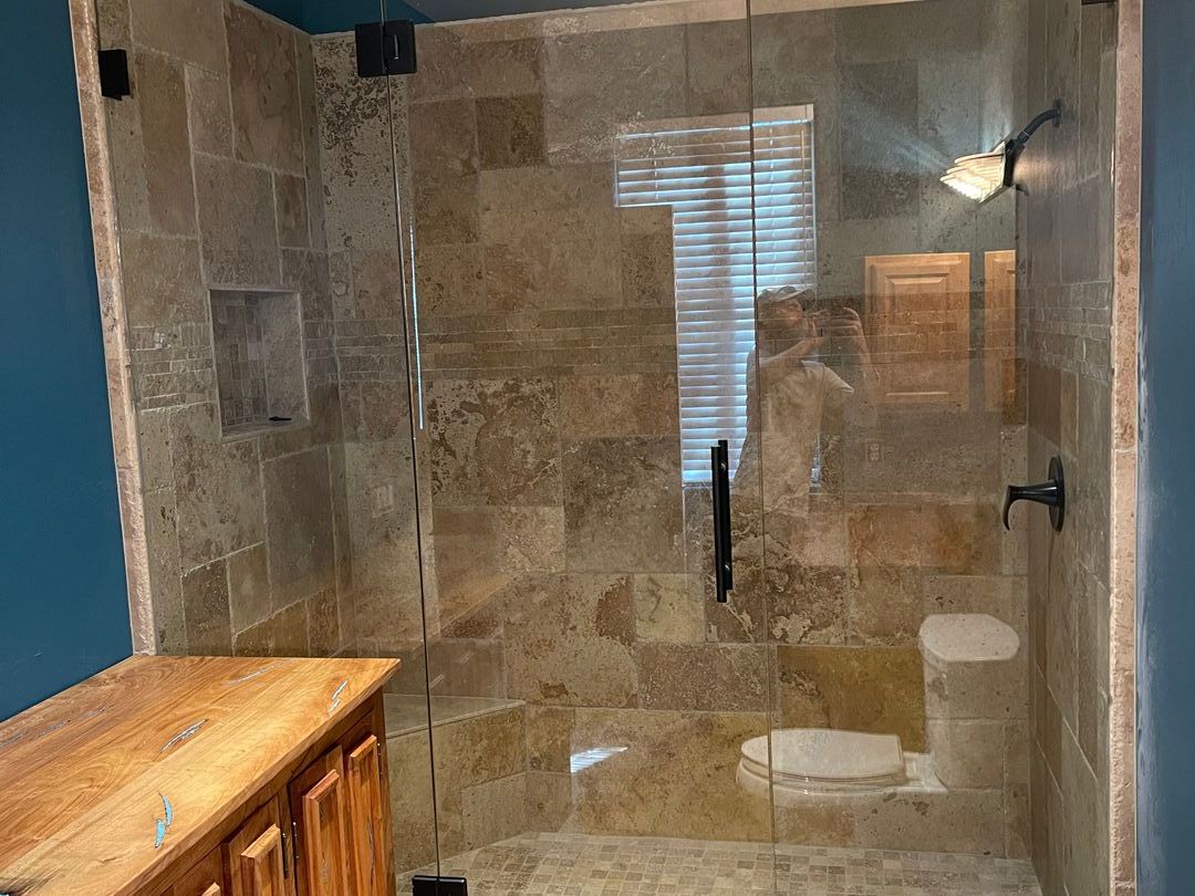 Frameless glass shower enclosure in travertine tile against a deep blue wall