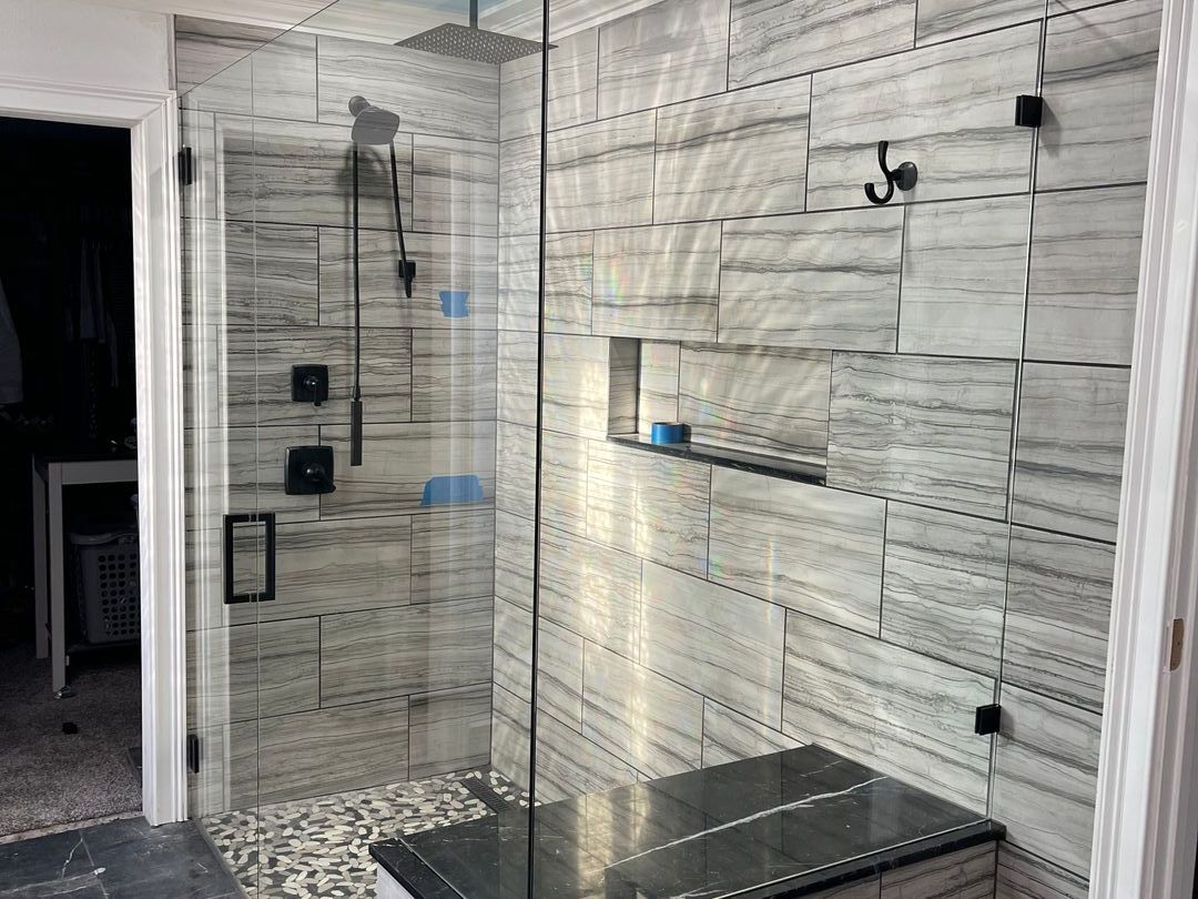 Frameless glass shower enclosure with grey striated tile and matte black hardware