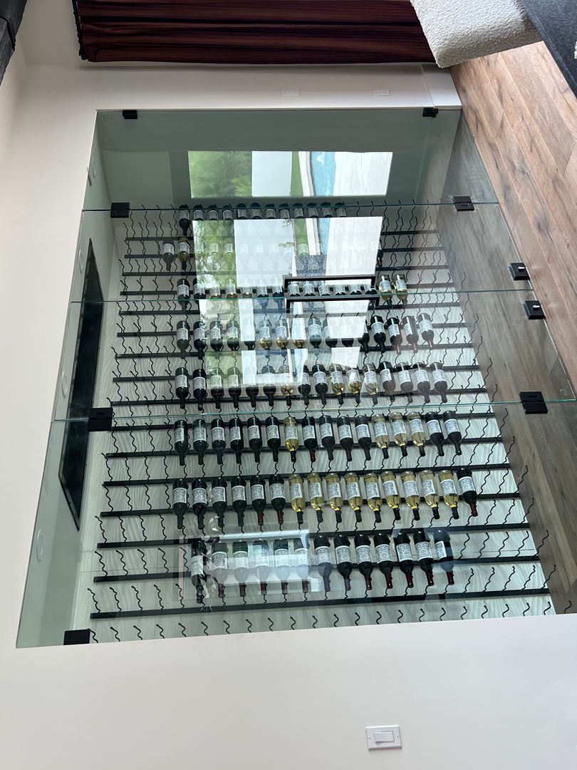 Glass-walled wine cellar viewed from above with racked bottles