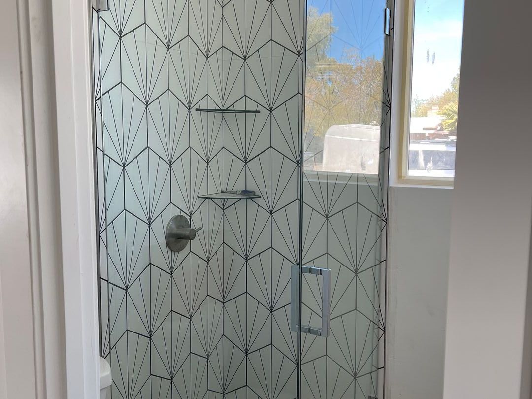 Frameless glass shower door against art deco starburst tile