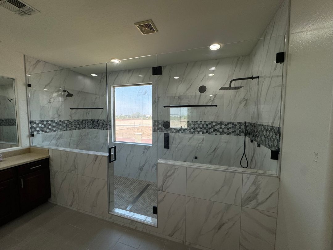 Large frameless glass shower enclosure with marble tile and a hexagon mosaic accent band