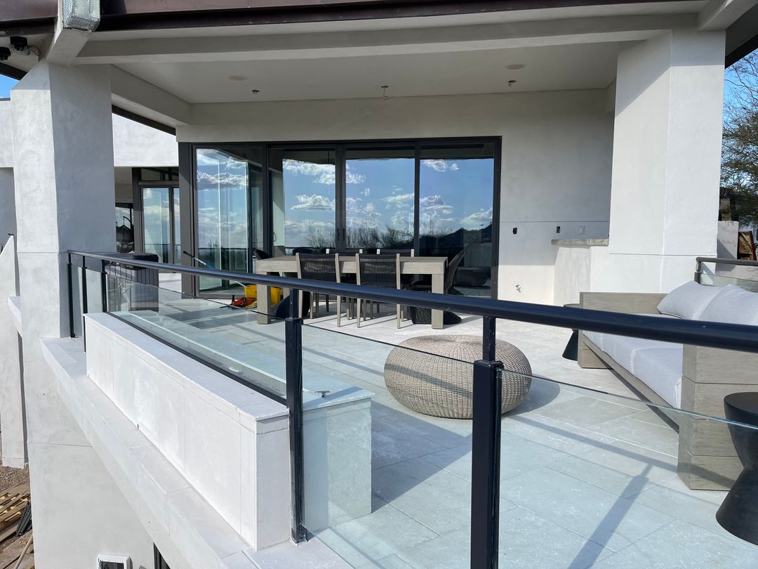 Glass railing around a covered patio with outdoor dining and lounge seating